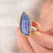 A hand carved tanzanite feather stone ring with a gold bezel and sterling silver band