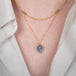 Gold necklace with a leaf-shaped tanzanite pendant on a person.
