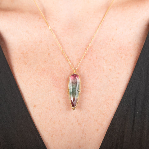 Handmade gold necklace with a watermelon tourmaline gemstone pendant on a person