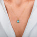 A gold necklace featuring a teardrop-shaped aquamarine necklace, shown worn on a model's neck.