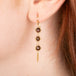 Gold earrings featuring trios of brown diamonds, shown worn in a person's ear.
