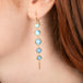 Gold earrings featuring golden hills turquoise stones worn in a person's ear.