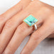 A gold and silver ring featuring a Variscite stone worn on a hand.