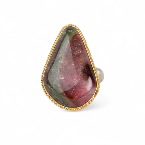 Ring with a teardrop-shaped watermelon tourmaline gemstone in a gold bezel with a sterling silver band on a white background