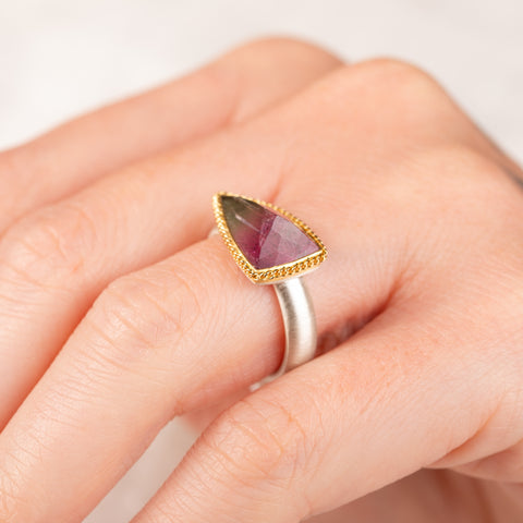 Close up of hand wearing a watermelon tourmaline ring with gold bezel and silver band