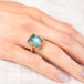 Gold ring with a rectangular aquamarine gemstone on a hand