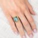 Gold ring with a rectangular aquamarine gemstone on a hand