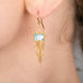Gold earring with a blue aquamarine gemstone worn by a person