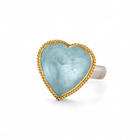 Heart-shaped ring with aquamarine stone, gold bezel and silver band on a white background