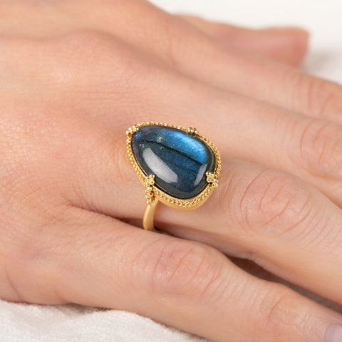 Gold ring with a blue labradorite stone on a hand