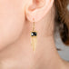 Gold earring with a black diamond worn by a person
