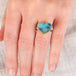 Hand wearing a boulder opal heart ring with a gold bezel and silver band