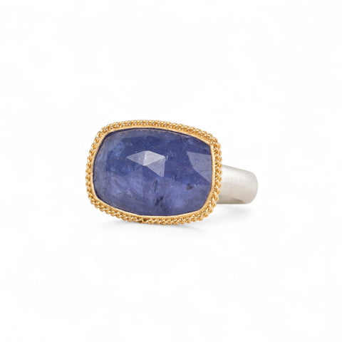 Tanzanite ring with gold bezel and sterling silver band on white background