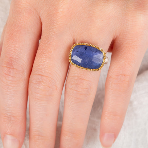 Hand wearing a tanzanite gemstone ring with gold bezel and silver band