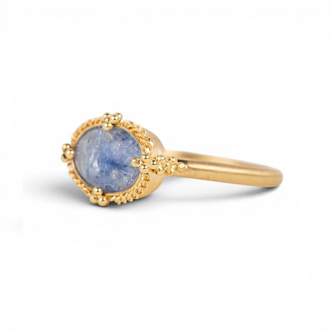 Gold ring with a blue dumortierite stone on a white background