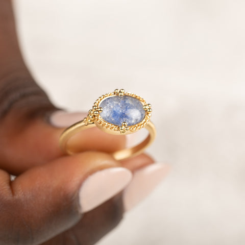 Gold ring with a blue dumortierite held in hand