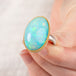 Hand holding an Ethiopian opal ring with gold bezel and sterling silver band