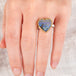 Hand wearing a boulder opal heart ring in an 18k gold bezel with sterling silver band
