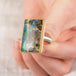 Hand holding a boulder opal ring in 18k gold bezel and sterling silver band
