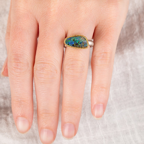 Hand wearing a boulder opal ring with gold bezel and sterling silver band
