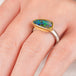 Close up of hand wearing a boulder opal ring with gold bezel and sterling silver band