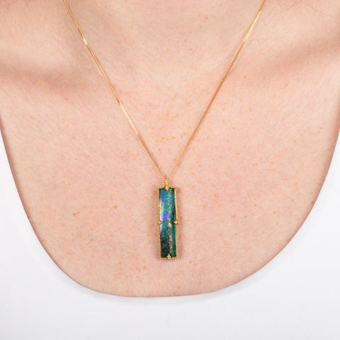 Boulder opal necklace with a handcrafted gold setting on a person