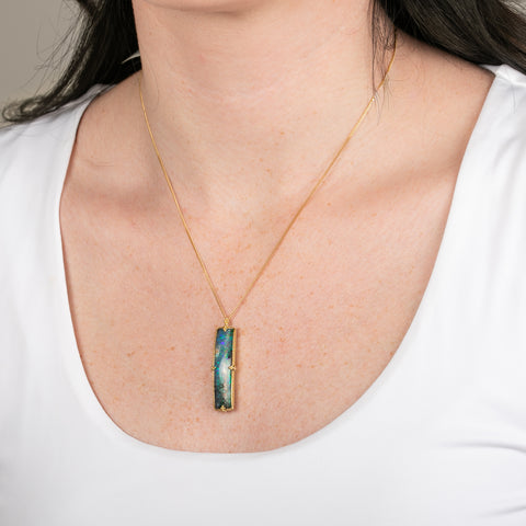 Boulder opal necklace with a handcrafted gold setting on a person
