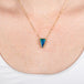 Gold necklace with a triangular boulder opal pendant on a person