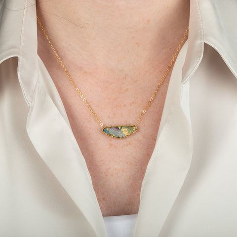 Boulder opal necklace with gold chain on a person