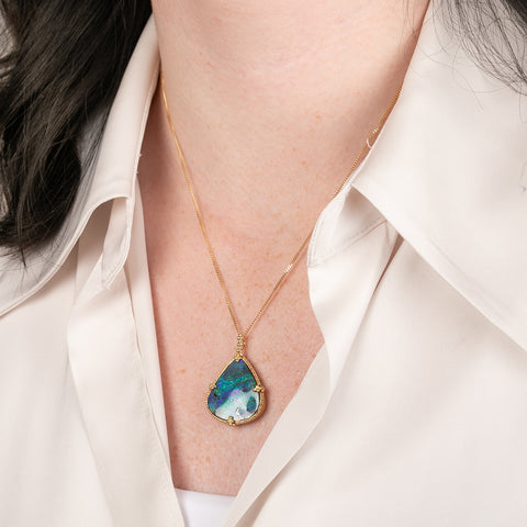 18k gold necklace with a boulder opal gemstone on a person