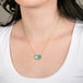 Necklace with a heart-shaped boulder opal stone pendant on a gold chain against a person