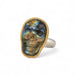 Skull-shaped labradorite ring with gold bezel and silver band on white background