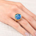 Gold ring with a moon face moonstone on a hand against a white background