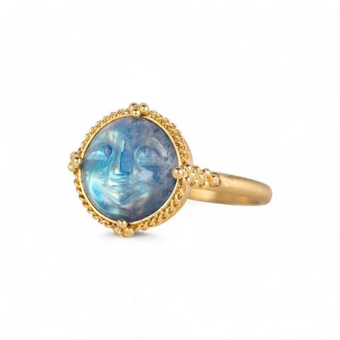 Gold ring with a carved moonstone on a white background