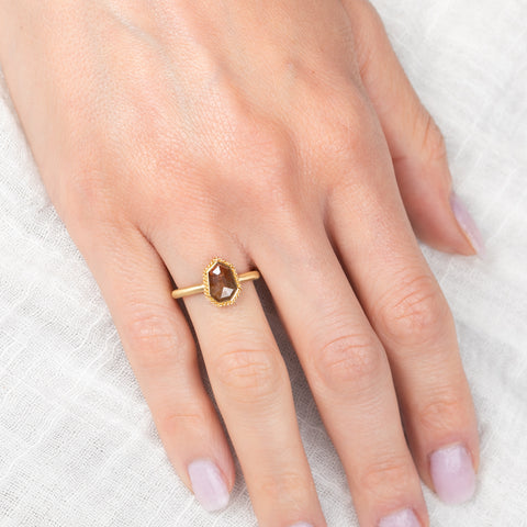 Gold ring with a diamond on a hand against a white background