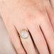 Opal ring on a person's finger with a neutral background