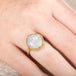 Gold ring with an ethiopian opal gemstone on a person's finger