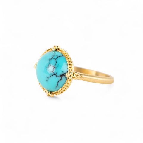 Gold ring with a turquoise stone on a white background