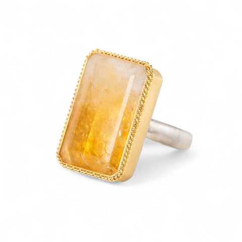 Ring with a large citrine stone, gold setting and silver band on a white background