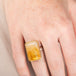 Ring with a large citrine stone, gold setting and silver band on a person's hand