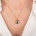 Gold necklace with a dark-colored diamond on a person wearing a white shirt