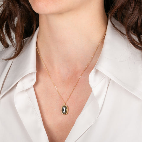 Gold necklace with a diamond worn by a person in a white shirt