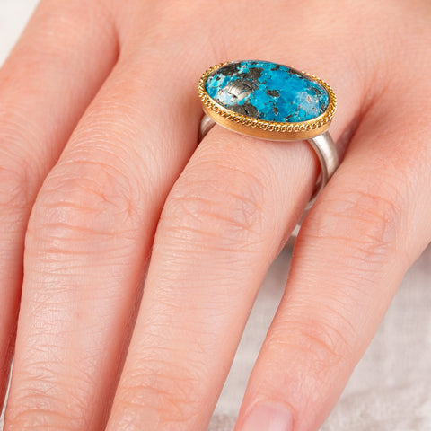 Hand wearing a turquoise fine jewelry ring with 18k gold bezel and sterling silver band
