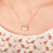 Gold necklace with a rectangular dendritic quartz pendant on a person wearing a lace top.