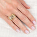 Gold and silver ring with a dendritic quartz stone on a hand against a white background