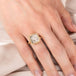 Gold ring with a dendritic quartz stone on a person's finger against a light background