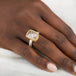 A gold and silver ring featuring a dendritic quartz stone with a detailed tree branch pattern inside, on a person's finger.