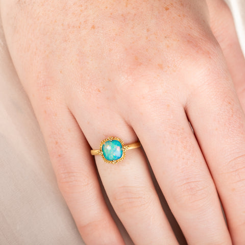 Gold ring with an Ethiopian opal stone on a hand