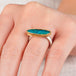 A hand wearing a boulder opal ring with an 18k gold bezel and sterling silver band