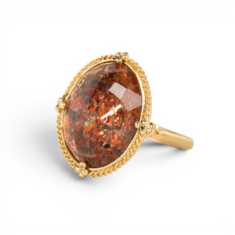 Gold ring featuring a sunstone gemstone on a white background